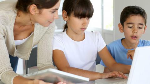 A mother helps her two children complete their homework
