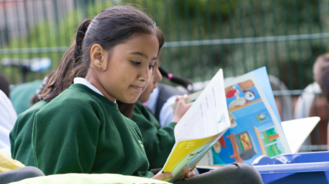 Student in uniform reading a book in the school library
